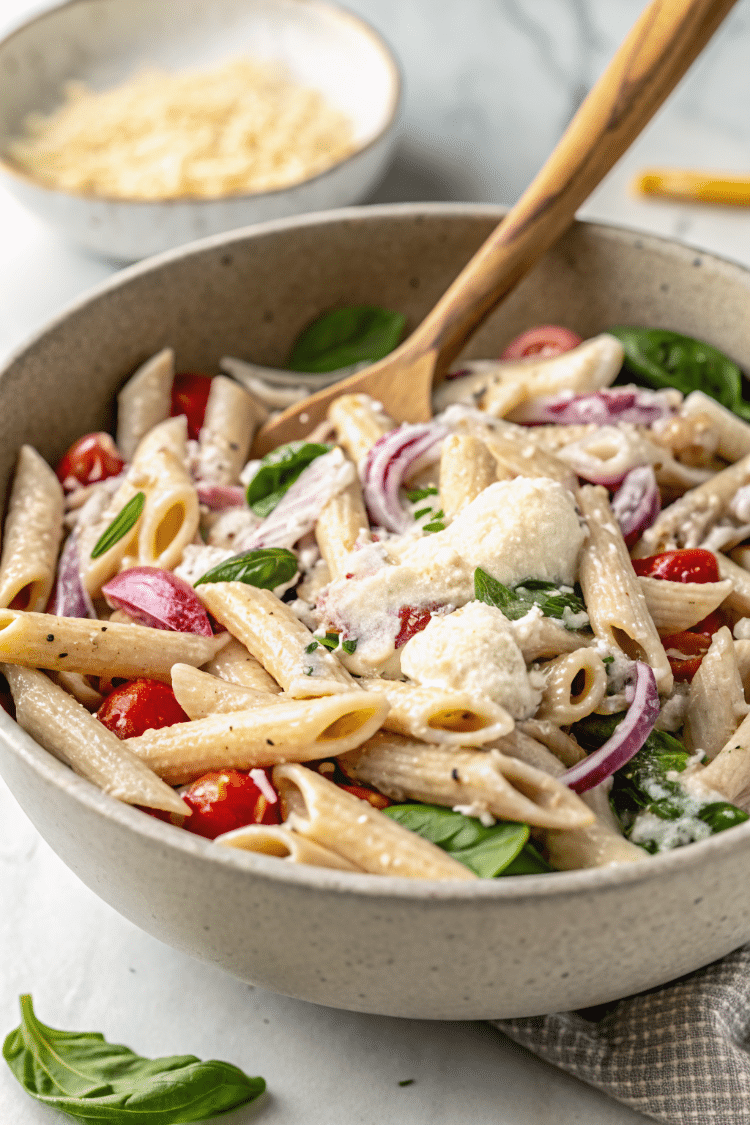zoomed in image of pasta salad ingredients in a clay colored bowl