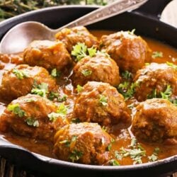 Indian style meatball curry in a skillet with a spoon.