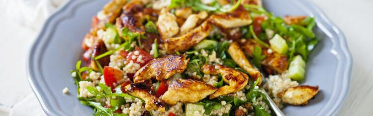 Seared chicken and quinoa salad on a powder blue plate over a white tablecloth.