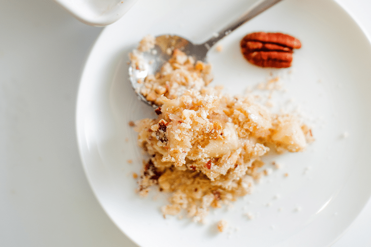 top view of a serving of apple crumble with a whole pecan in the top right corner