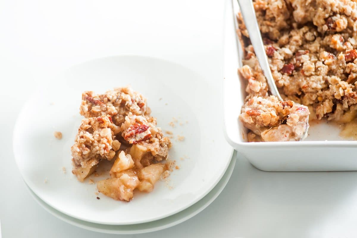 warm apple crumble with oats and cinnamon on a white plate
