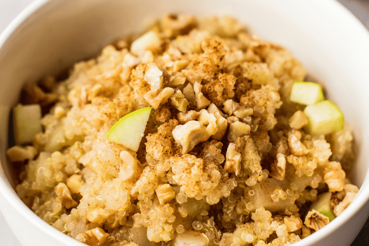 zoomed in image of cooked quinoa with chopped apples, cinnamon, walnuts, and maple syrup.