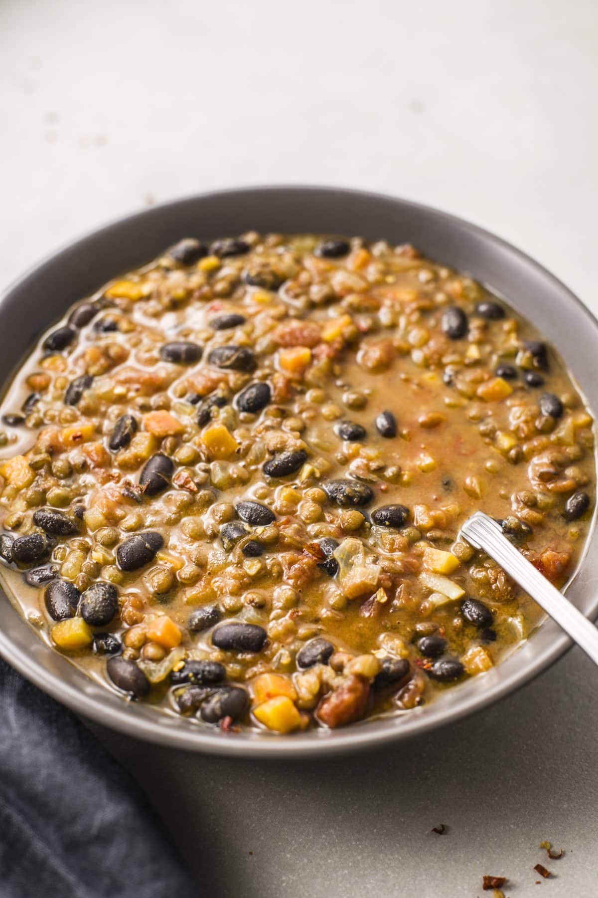 Gray bowl of plant-based soup full of beans and lentils