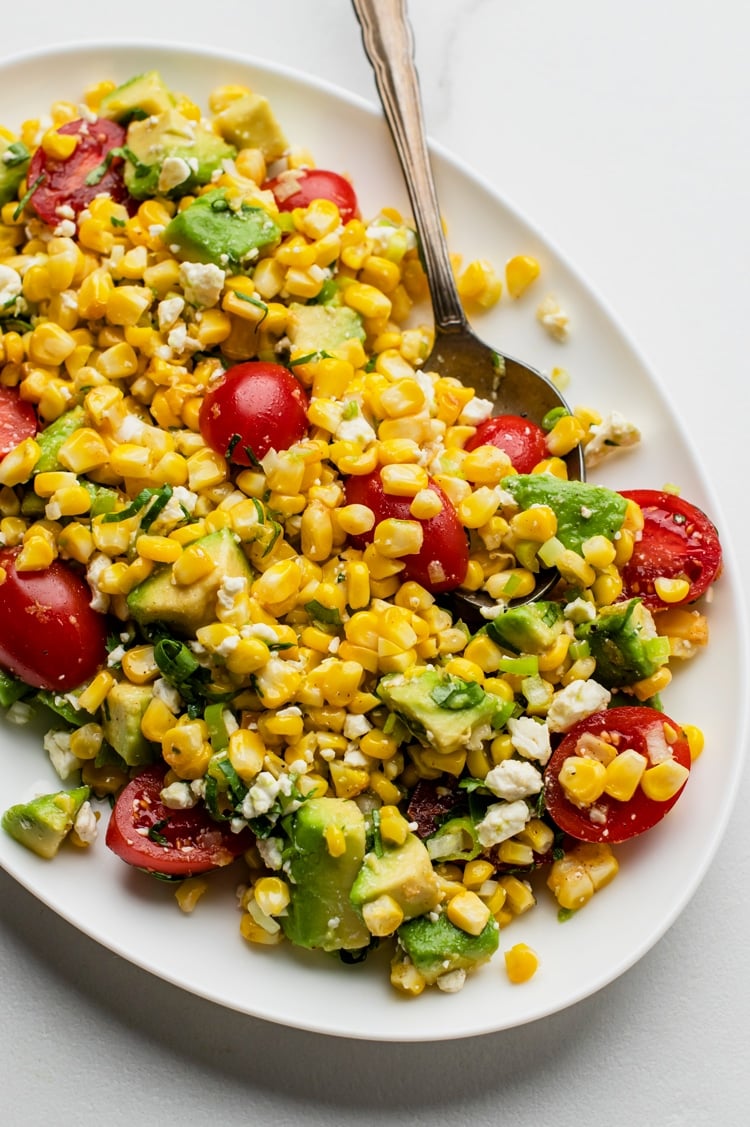 Achieve crunchy, creamy, sweet, salty, and slightly spicy, all in one bowl, with this elote tomato avocado salad recipe. 