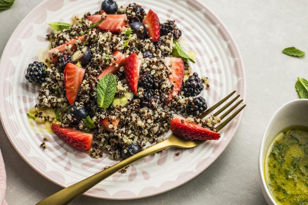 Fresh strawberries, blueberries, and black berries mixed into a healthy quinoa salad