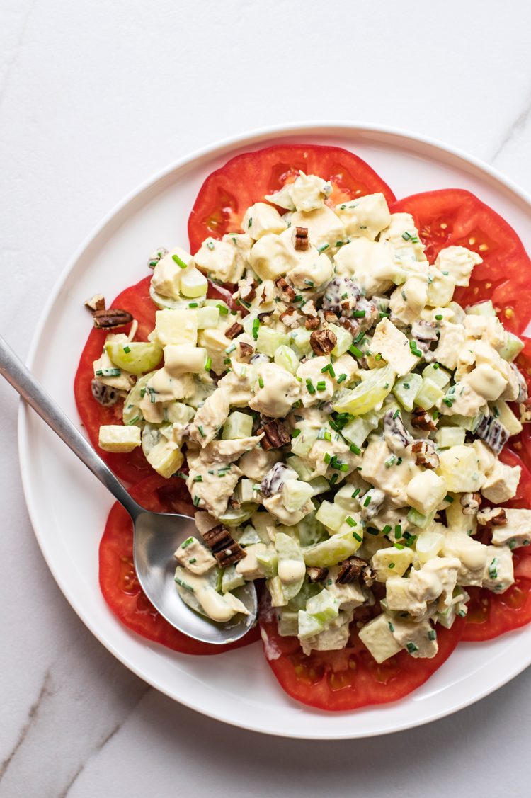 skinny mustard chicken salad atop sliced tomato on a a white plate
