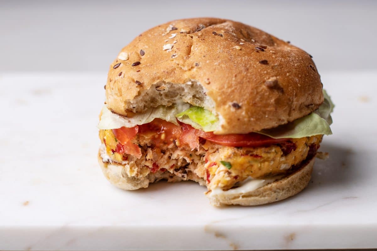 baked salmon burger on a white marble slab with a bite taken out of it