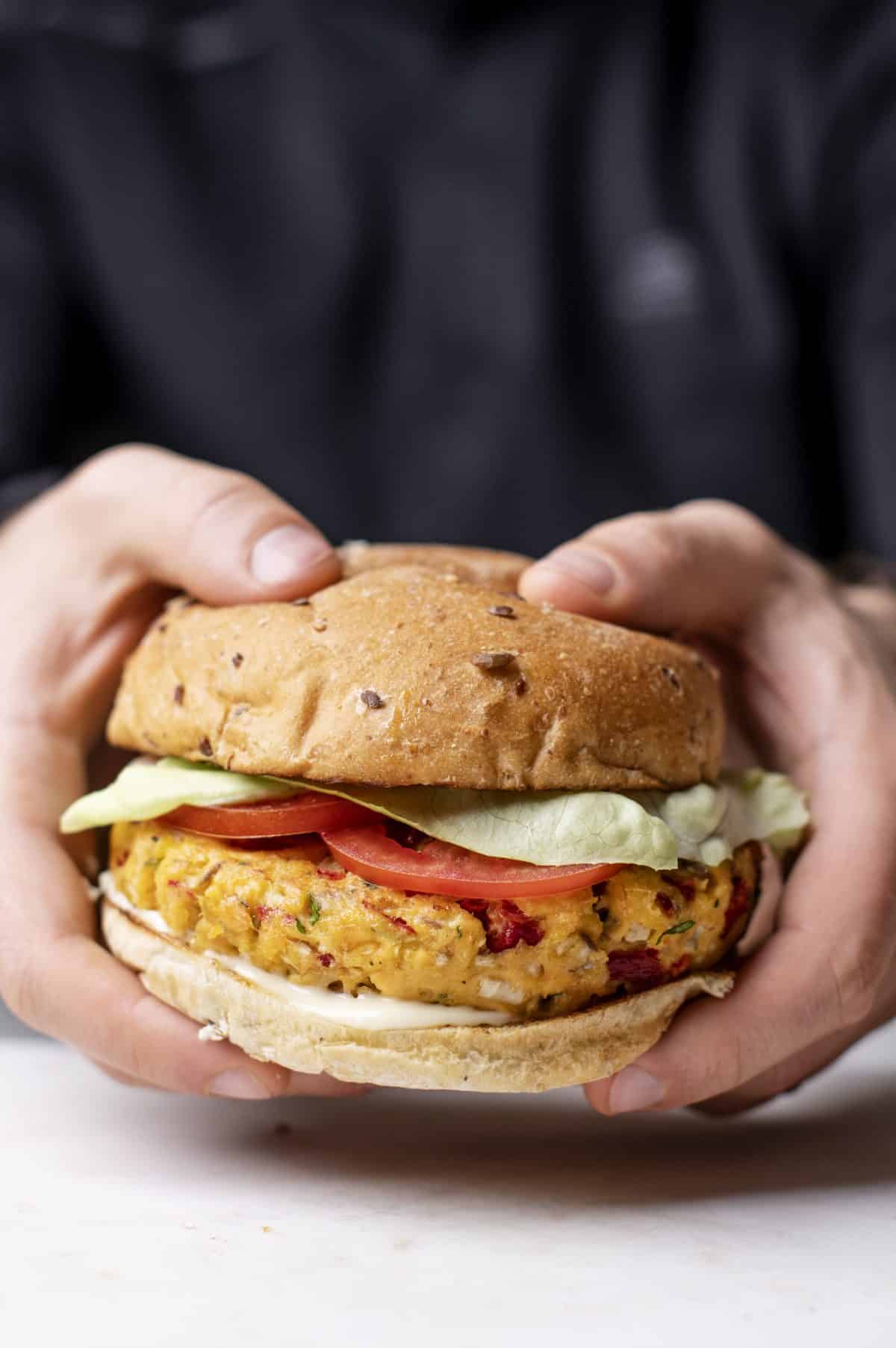 person holding a healthy baked salmon burger with both hands