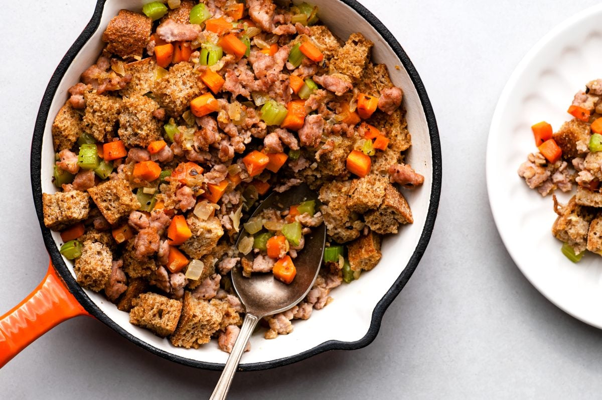 ezekiel bread stuffing in a pan with a spoon and some stuffing on a plate beside it