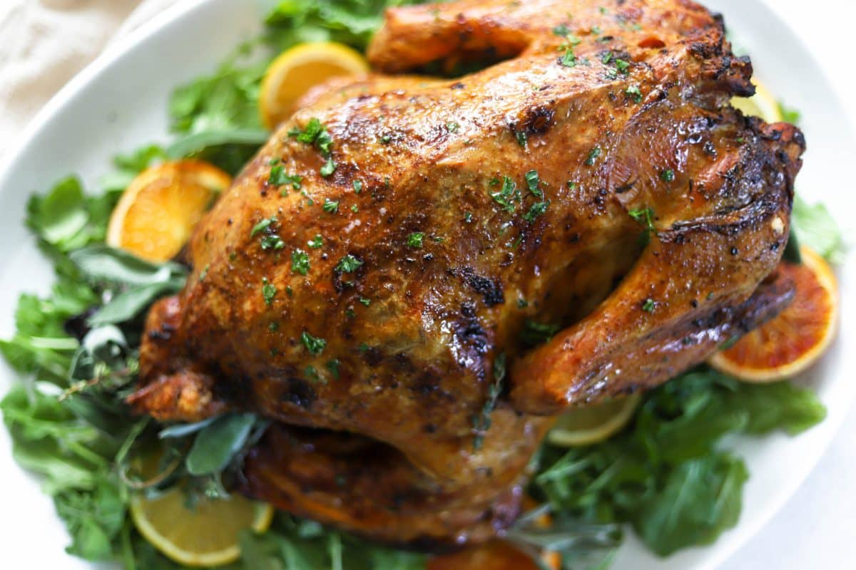Whole roasted turkey from above on a platter with greenery and orange slices