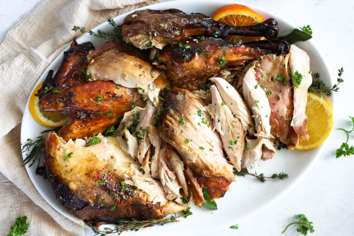 Fully cooked ans sliced up turkey on a white platter
