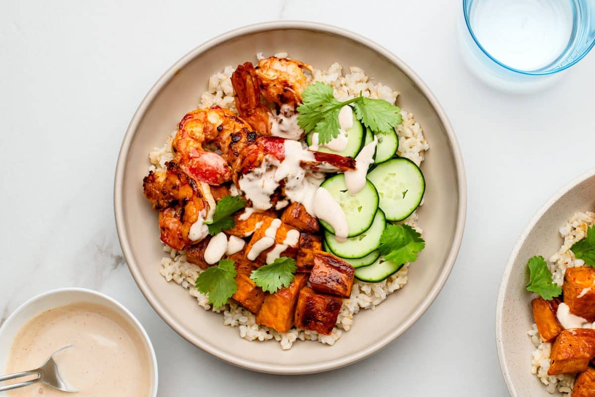 Healthy grain bowl with shrimp, rice, sweet potatoes, cucumbers, and more.