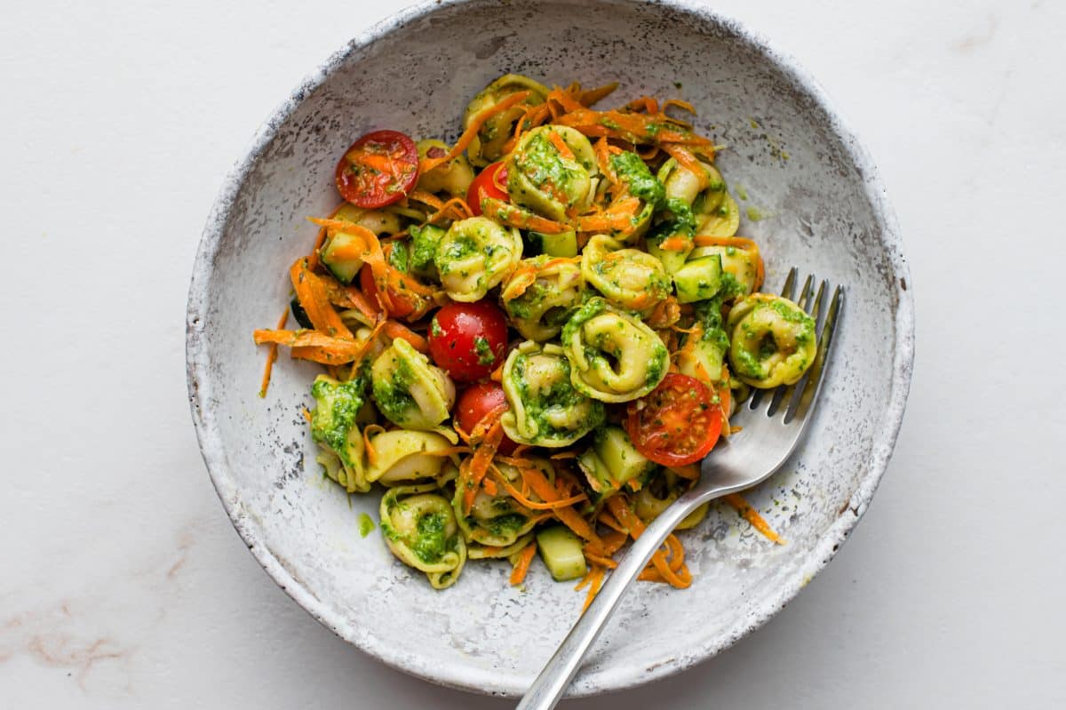 pesto tortellini pasta salad in a grey bowl.