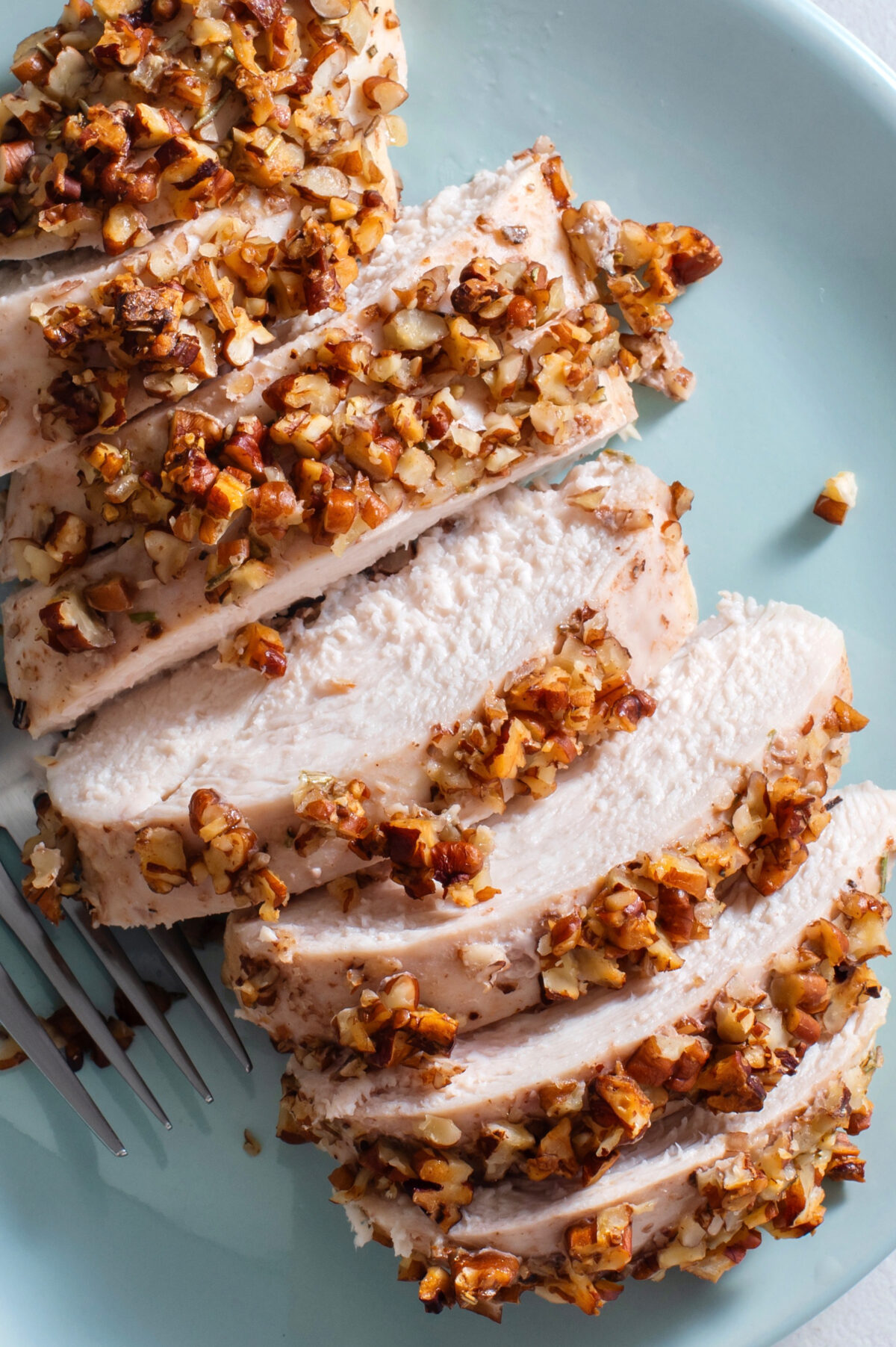 sliced pecan crusted chicken on a blue plate