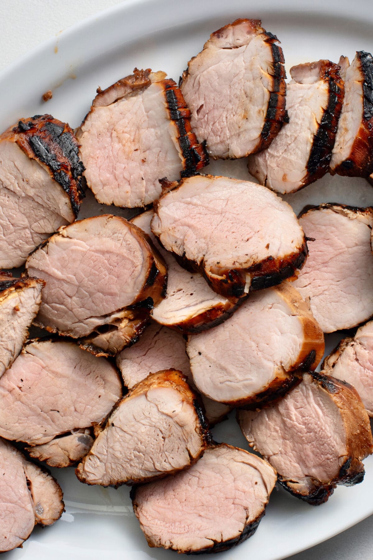 sliced bourbon pork rounds on a white serving platter