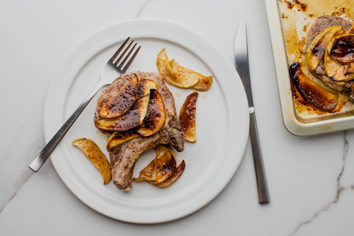 pork chop with apple slices on a plate with a fork