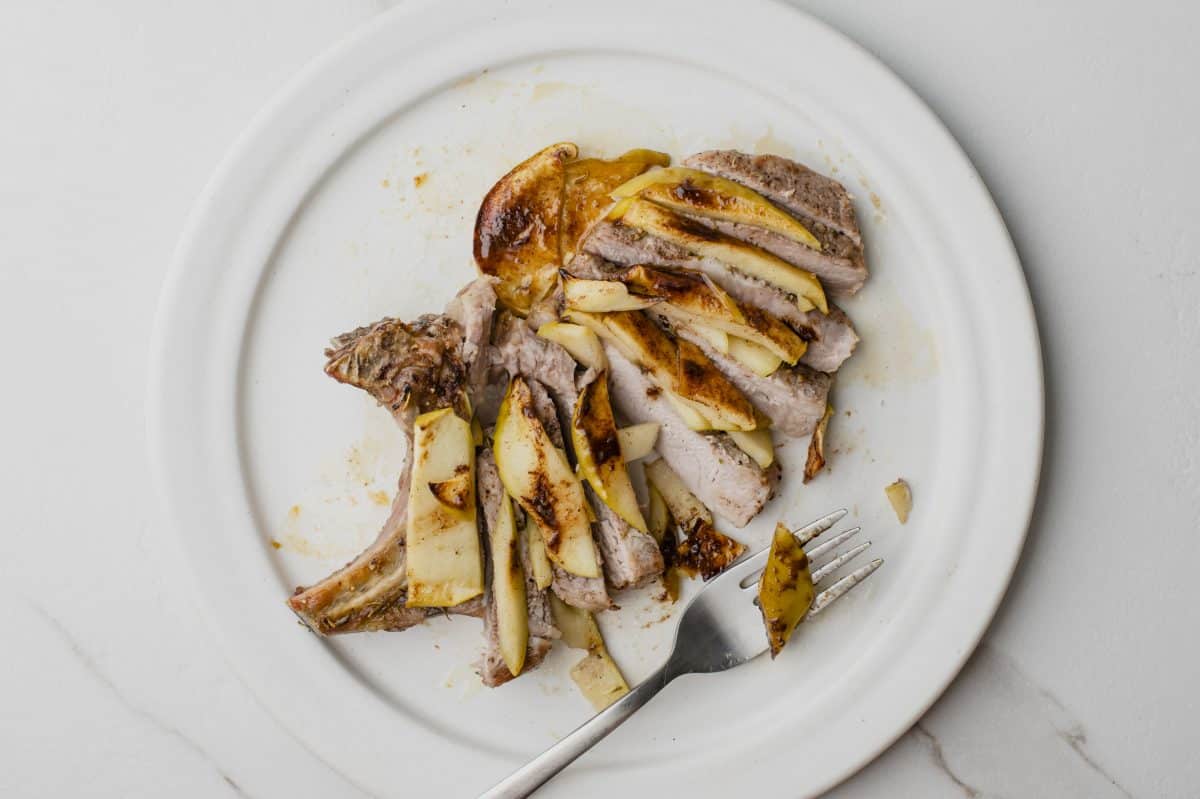 sliced up cooked pork chop on a white plate ready to eat