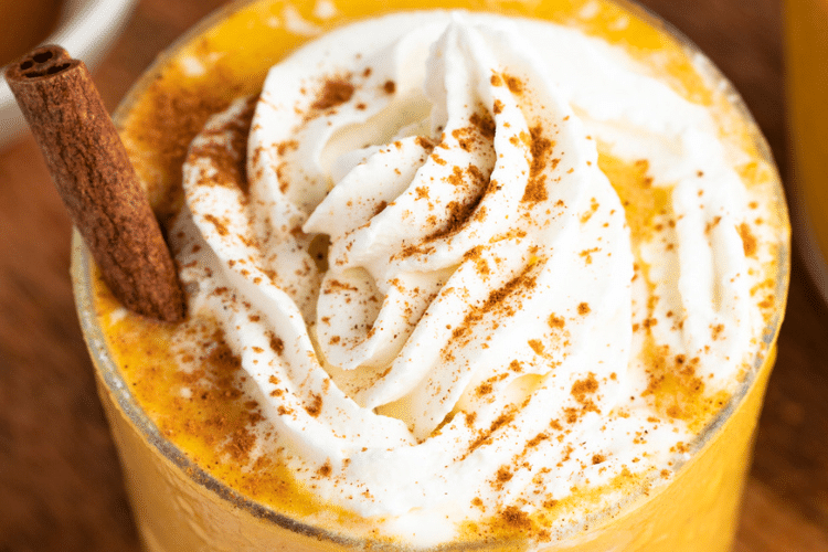 close up image of whipped cream on top of smoothie sprinkled with cinnamon