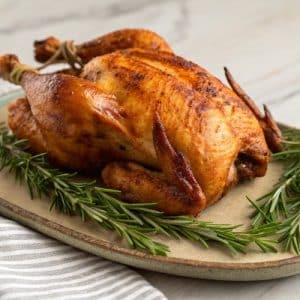 Instant Pot "Rotisserie" Chicken on a platter with rosemary sprigs.