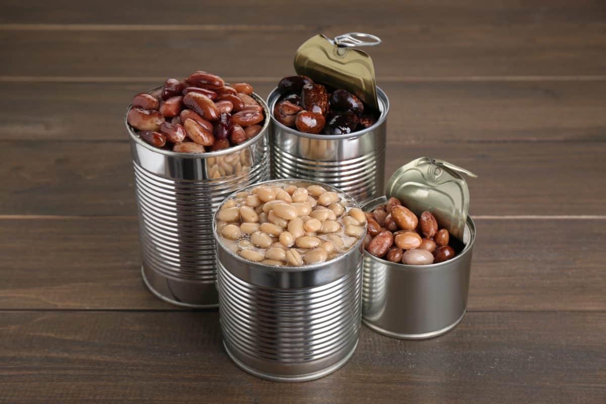 Varieties of canned beans over a wooden surface.