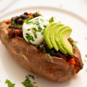chili-stuffed sweet potato on plate with toppings