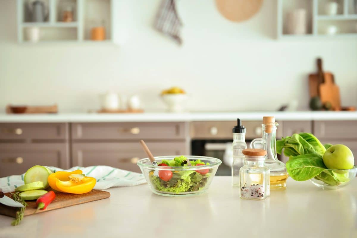 A kitchen island with ingredients and other fixings for making a salad.