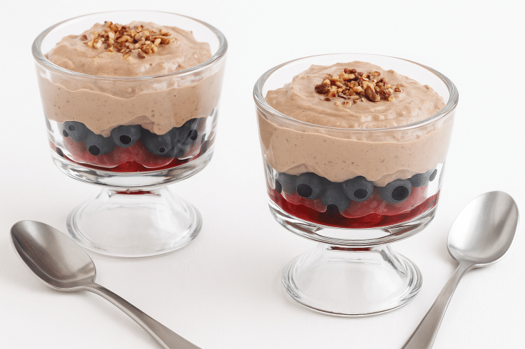 Two healthy breakfast sundaes with two spoons next to them